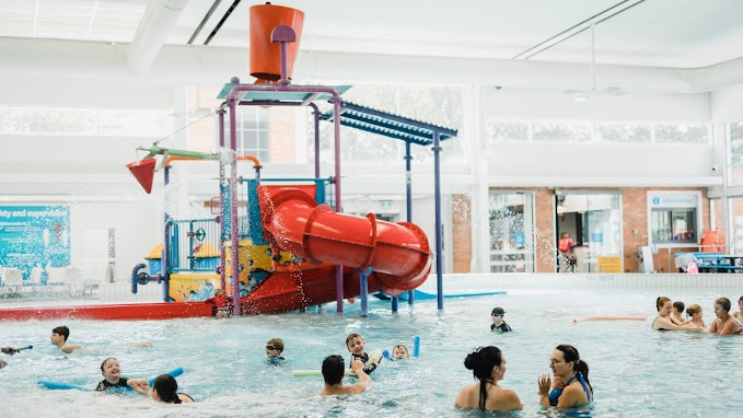 People in a pool underneath a waterslide.