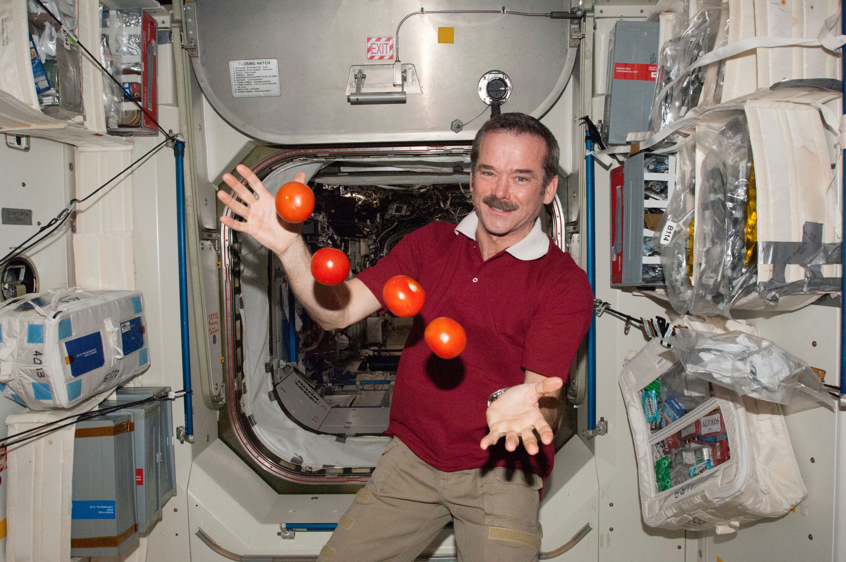 A man juggles tomatoes in zero gravity aboard the International Space Station.