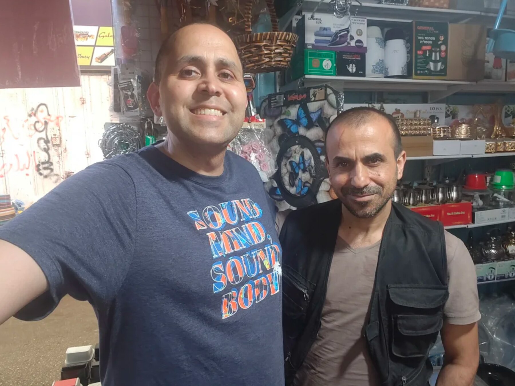 Hani and Majed stand in front of shelves displaying various objects.
