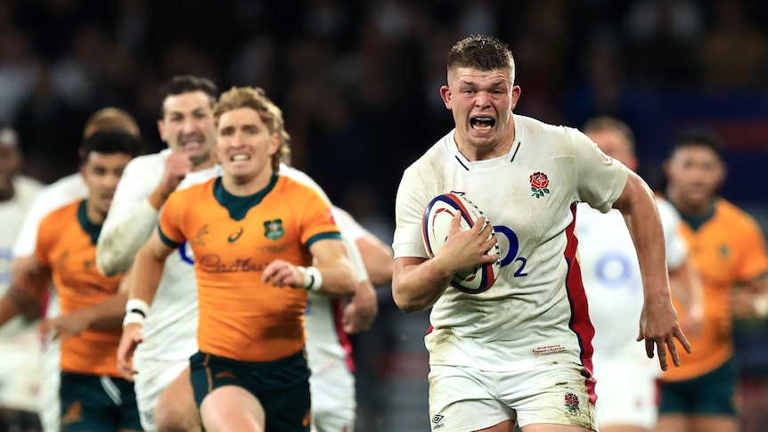 Jamie Blamire court la bouche ouverte et le ballon sous le bras, poursuivi par un certain nombre d'autres hommes