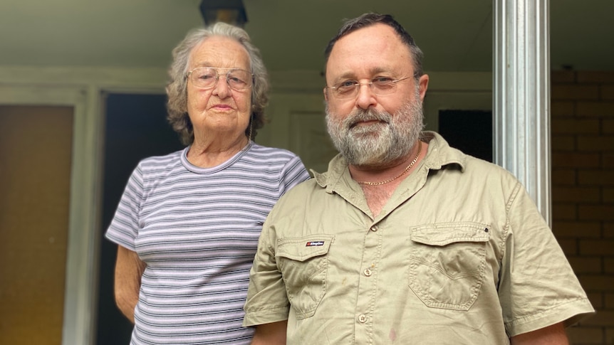 A mid shot of a man in his 60s and a woman in her 80s on the front step of a farmhouse