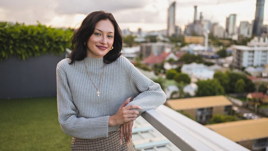Ksenia Borodin smiles as she leans on a balcony railing in a building in inner-city Brisbane. 