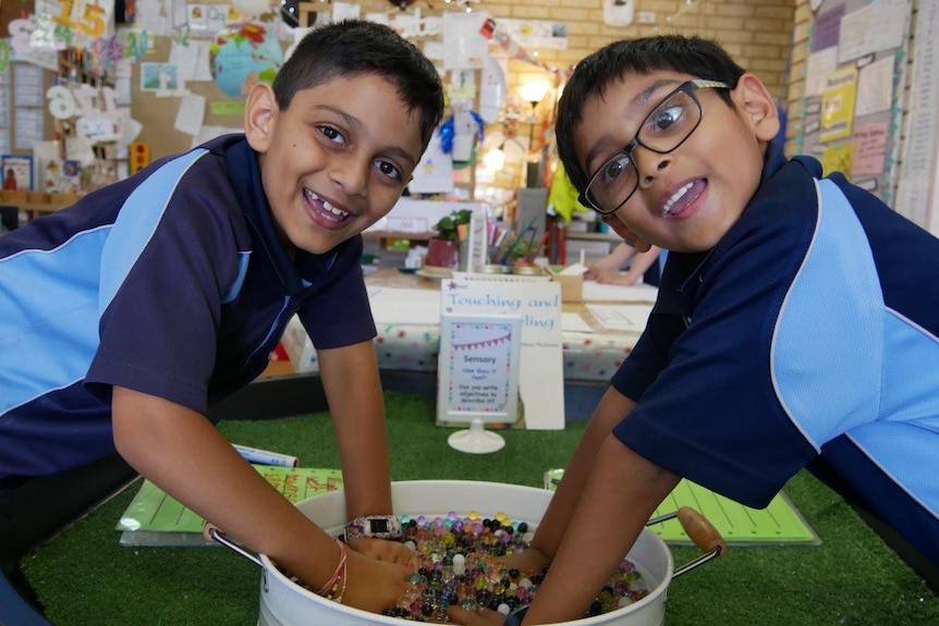 Two boys in class at Beaumaris Primary School pose for a photo smiling wearing blue uniforms.