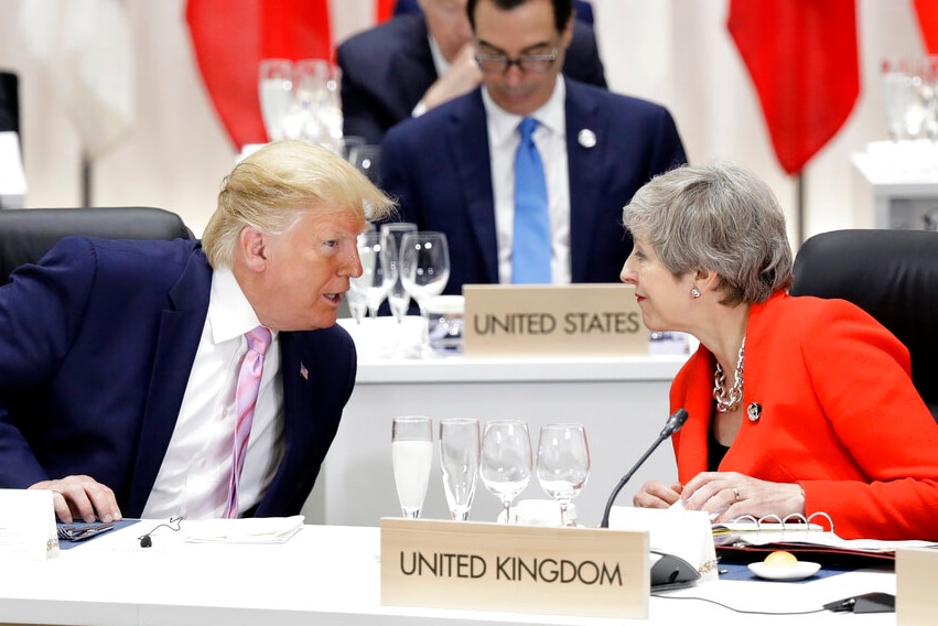 A man and woman talk while seated behind desks