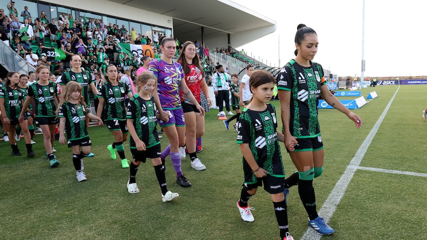 Two women's soccer teams and mascots walking out to play a match.