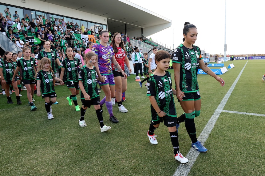 Two women's soccer teams and mascots walking out to play a match.