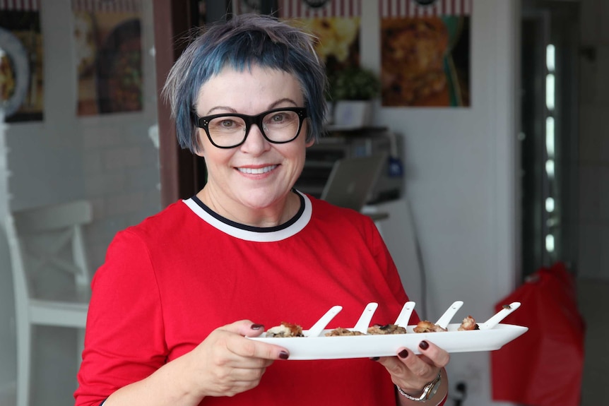 Karen McDonald standing in doorway of shop holding holding a tray of nibbles