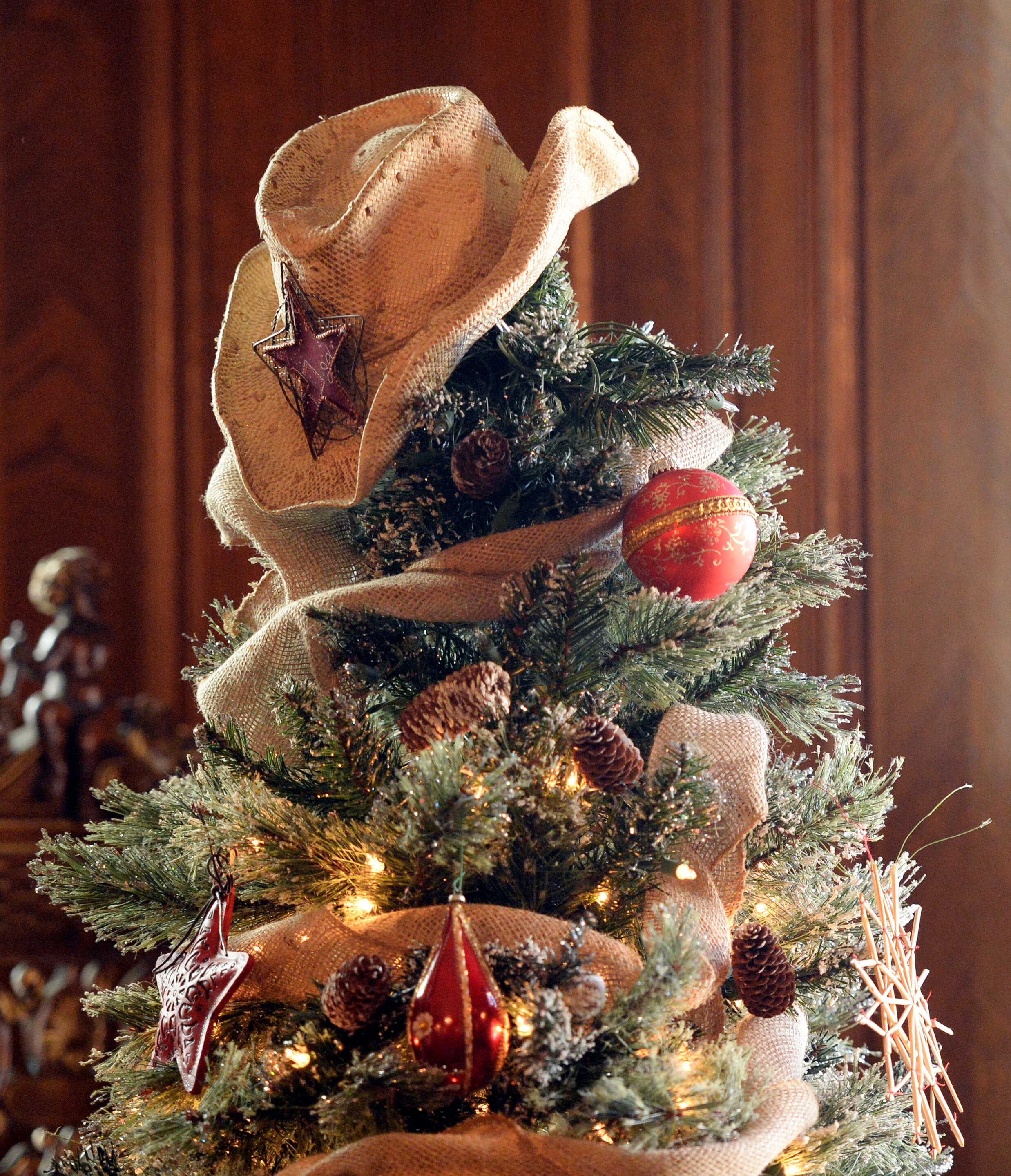 A ragged straw cowboy hat sits on top of a decorated Christmas tree