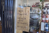 A sign on brown paper in a cafe window reads: We're hiring staff, looking for hospo all rounders
