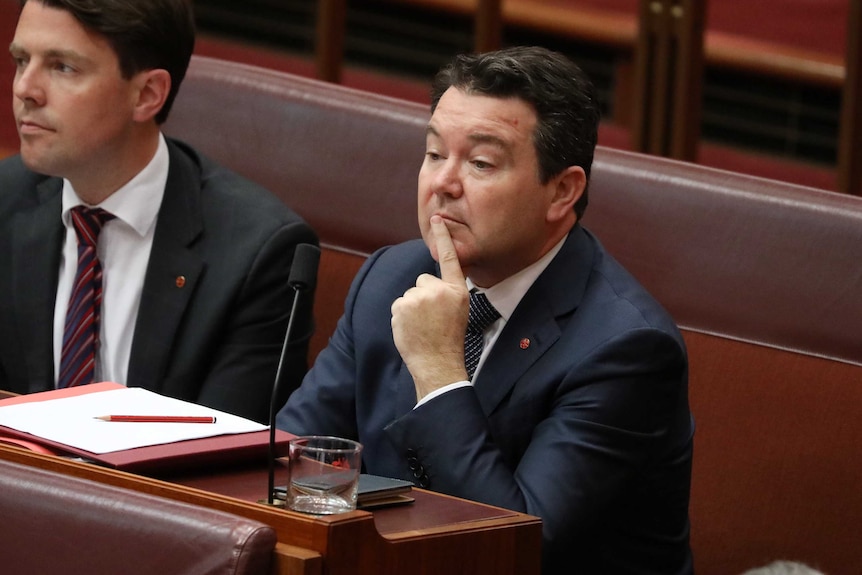 Dean Smith, with his pointer finger resting on his chin, sits in the Senate.