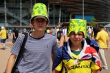 Two boys wearing green and gold cardboard buckets on their heads.