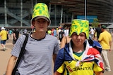 Two boys wearing green and gold cardboard buckets on their heads.