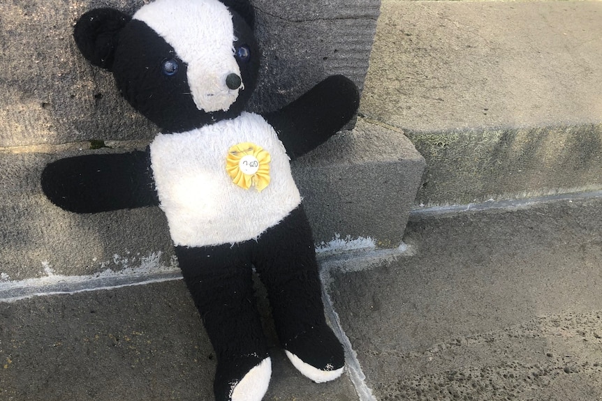 A very worn toy panda on concrete.