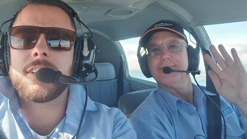 a young man and his father sitting in a plane