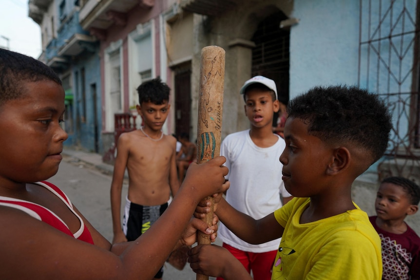 Un grupo de niños reunidos alrededor de un bate de béisbol en La Habana.