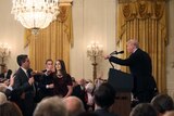 A White House staff member reaches for the microphone held by CNN's Jim Acosta as he questions Donald Trump.