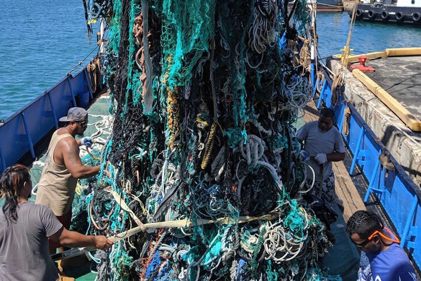A huge trawl of old and knotted fishing lines and other garbage is hauled up onto a boat