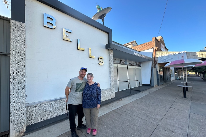 a man and older woman standing out the front of a building front