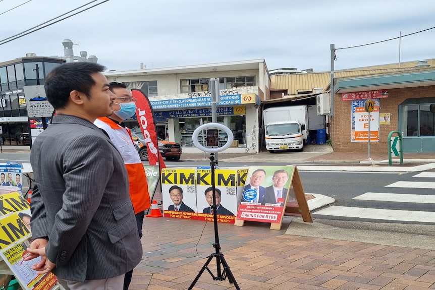 Simon Zhou campaigning at a pre-poll booth with signs for Peter Kim near by - supplied by Peter Kim