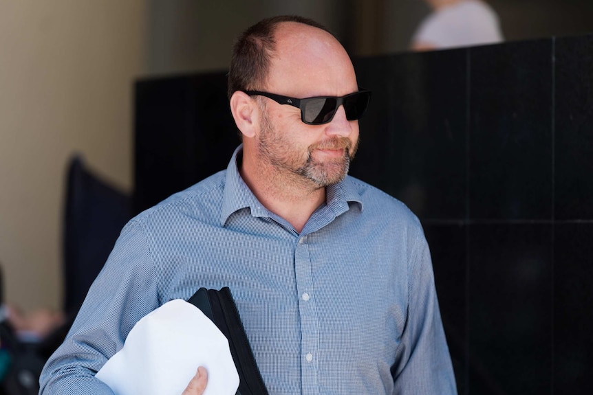 Former MP Barry Urban walks out of Perth Magistrates Court looking to one side.