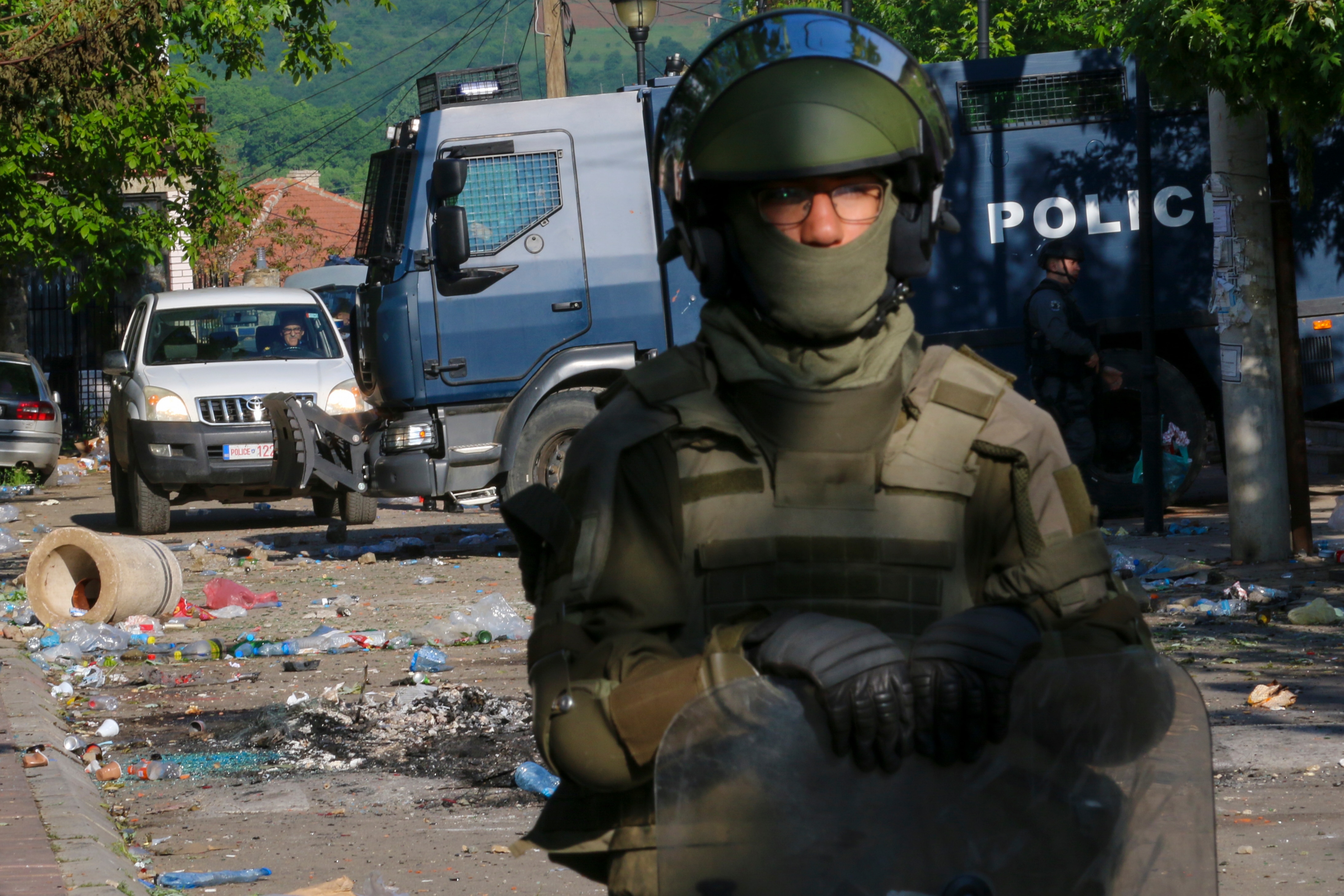 A soldier stands on the street surrounded by debris from protest.