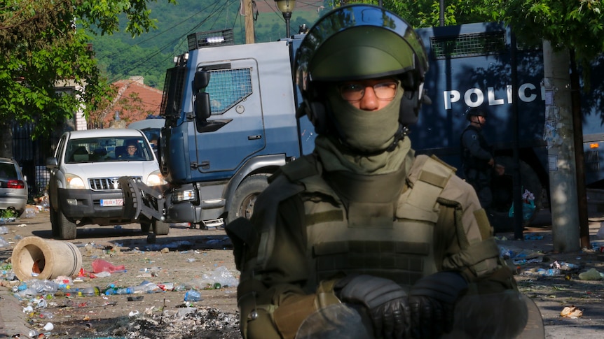 A soldier stands on the street surrounded by debris from protest.