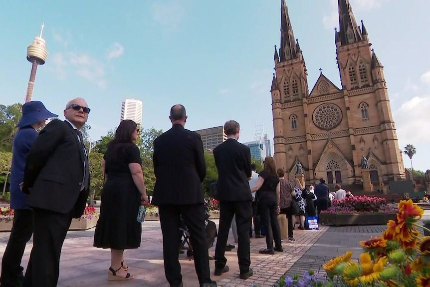 Men dressed in black line up outside cathedral