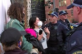 A woman wearing a mask speaks to police
