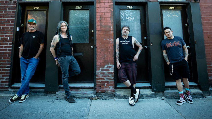 A 2023 press shot of NOFX outside a red brick building