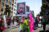 A man holds a defaced poster of Russian president Vladimir Putin