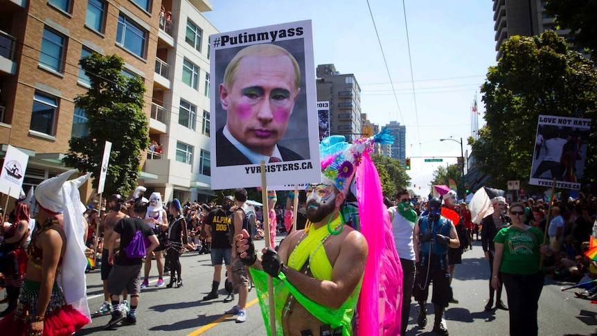 A man holds a defaced poster of Russian president Vladimir Putin
