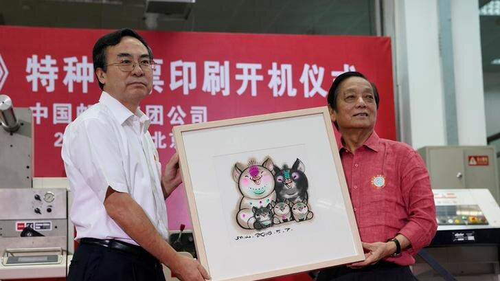 Men pose with picture of his Year of the Pig stamp that shows a five-member pig family