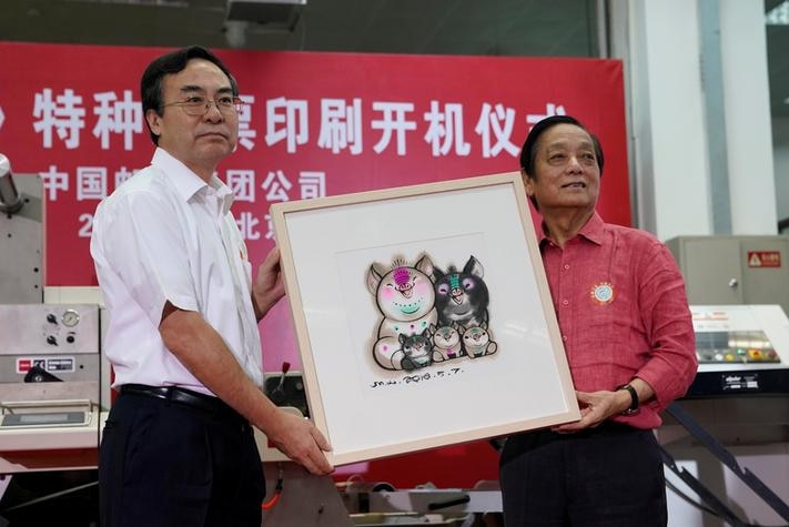 Men pose with picture of his Year of the Pig stamp that shows a five-member pig family