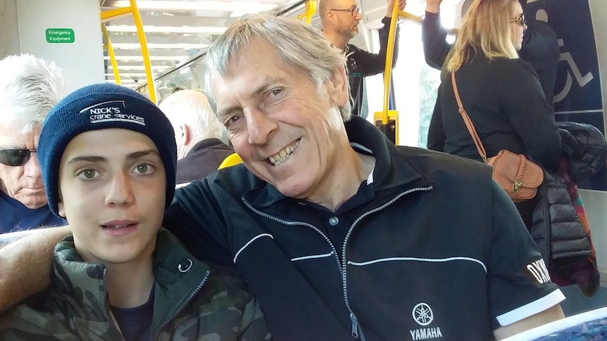 A man and his grandson on the tram smiling.