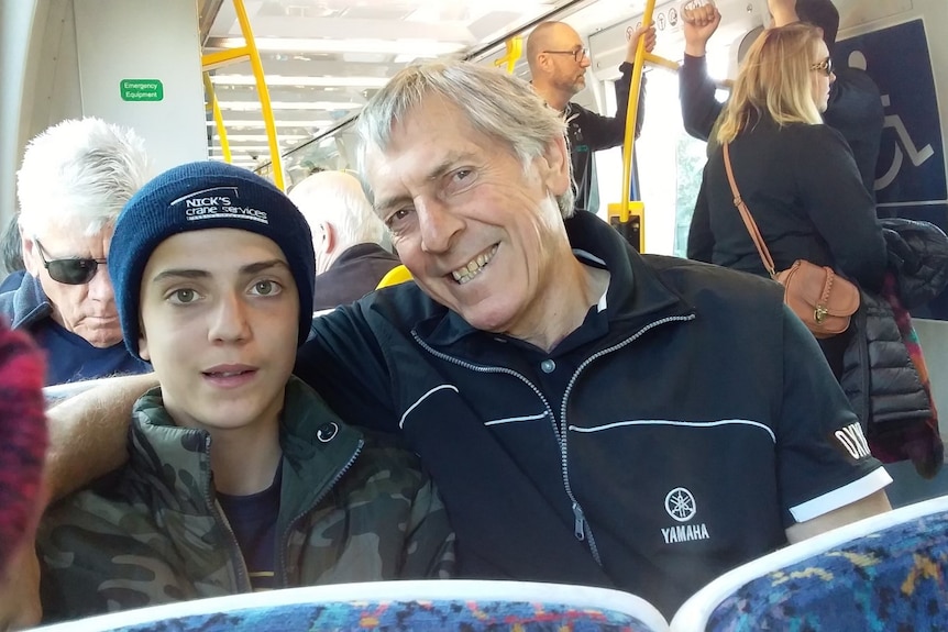 A man and his grandson on the tram smiling.