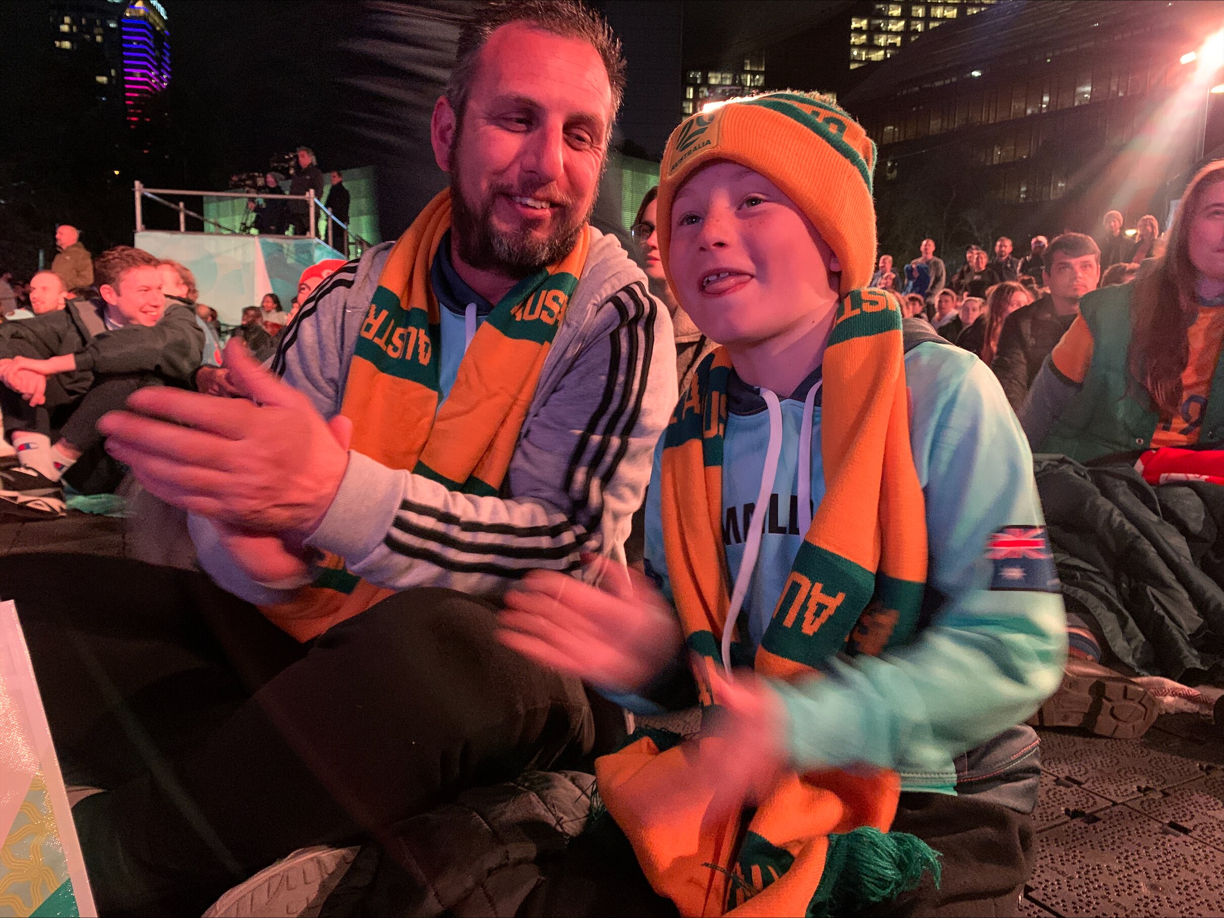 a father and son clapping at a football match fan site