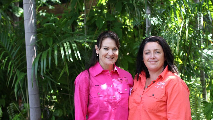 two women standing in front of a garden