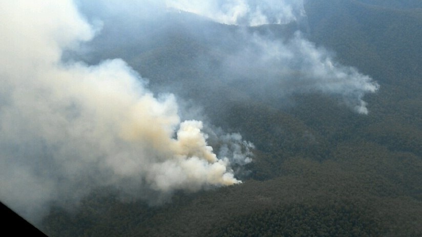 Smoke plumes billowing in steep mountain range.
