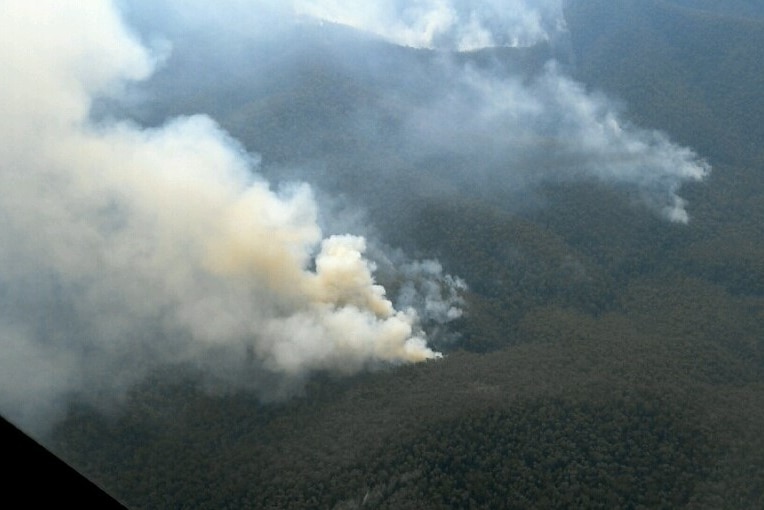 Smoke plumes billowing in steep mountain range.