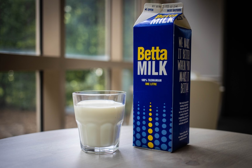 milk in a glass next to a milk carton