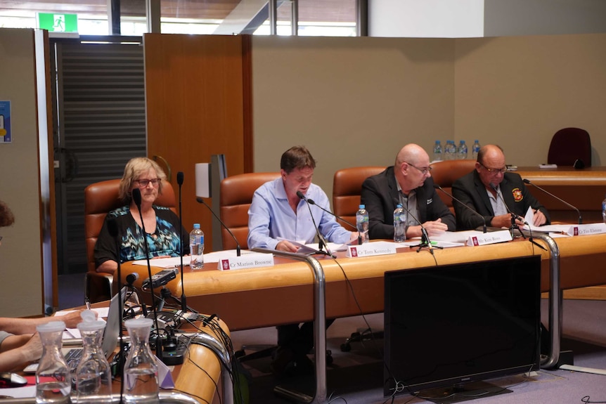 Councillors and general managers sitting in a council chamber.