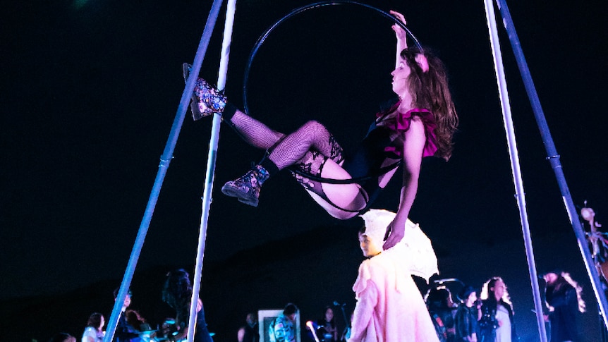 Aerial performer in a suspended hoop, on a nighttime beach film set
