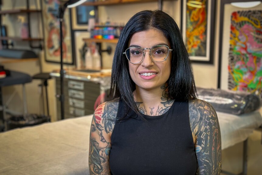 A heavily tattooed woman sits in a studio.