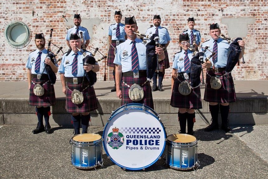 A pipes and drums band standing in front of a wall in Brisbane.