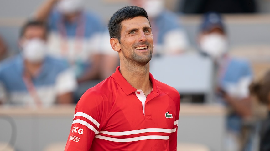 A smiling Novak Djokovic walks towards the net after winning the French Open.