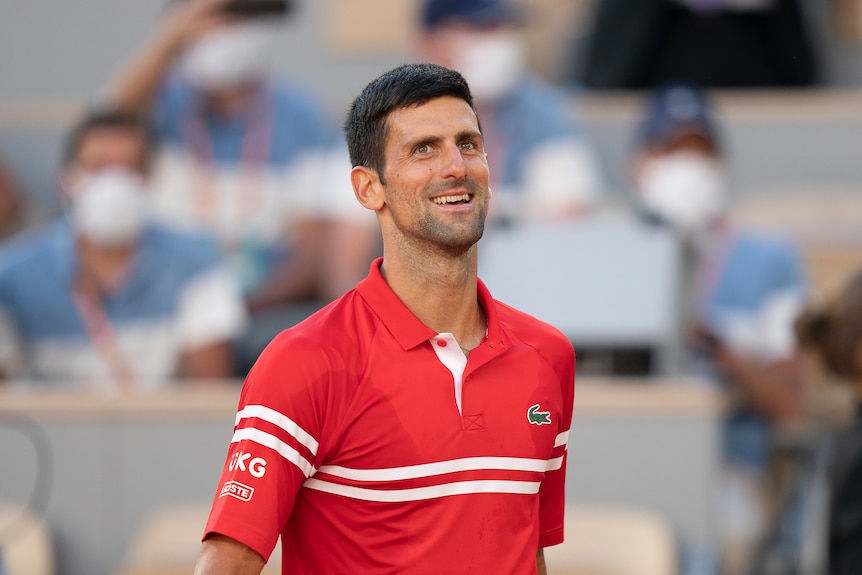 A smiling Novak Djokovic walks towards the net after winning the French Open.