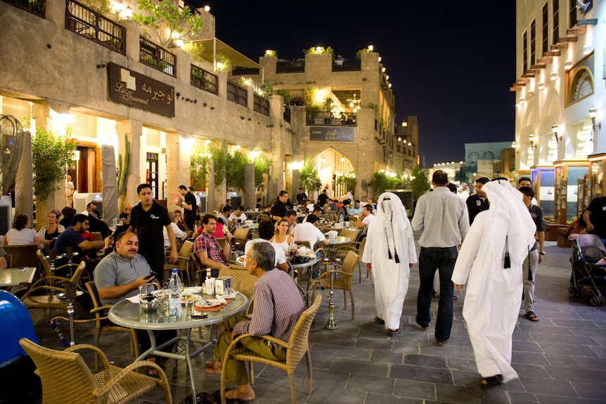 Men and women sit outdoors at a cafe at night