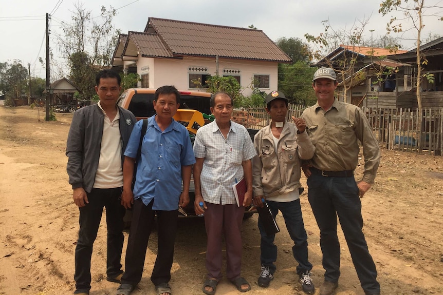 Leigh Vial (far right) stands with Laos farmers after a demonstration of the rice seeder.