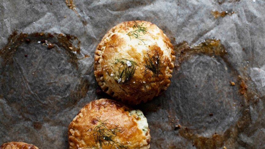 Four mini cheese and herb pies topped with sea salt and herbs, a party snack recipe for summer.