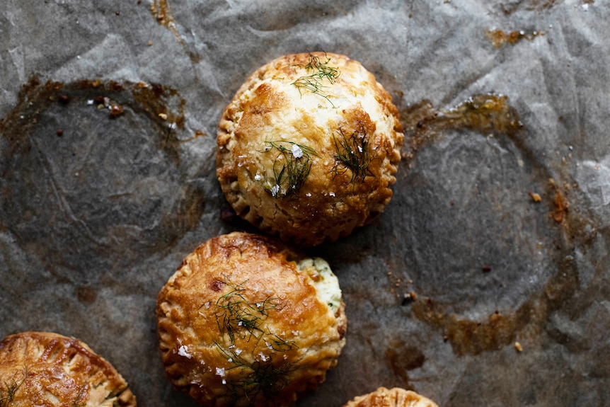 Four mini cheese and herb pies topped with sea salt and herbs, a party snack for summer.